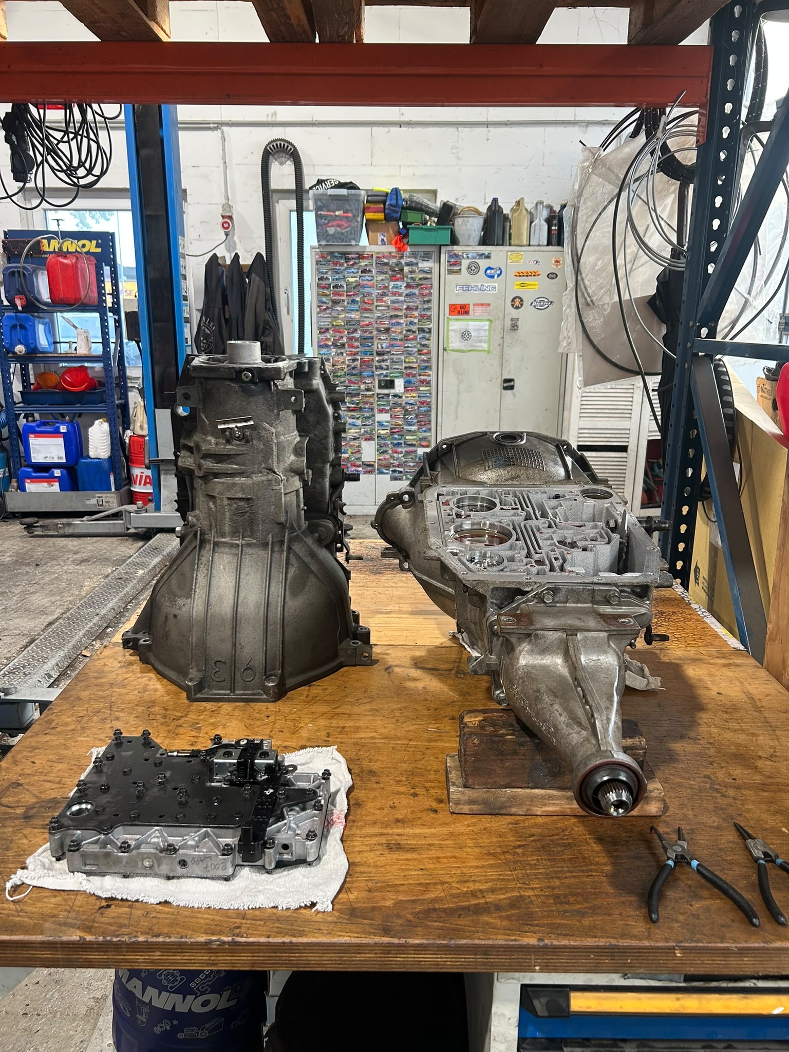 Ein zerlegtes Automatikgetriebe, ein Getriebegehäuse und ausgebaute Bauteile auf der Werkbank